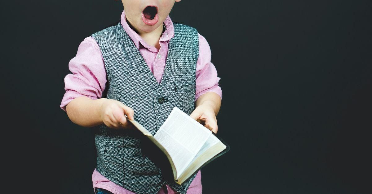 Boy holding a book looking shocked