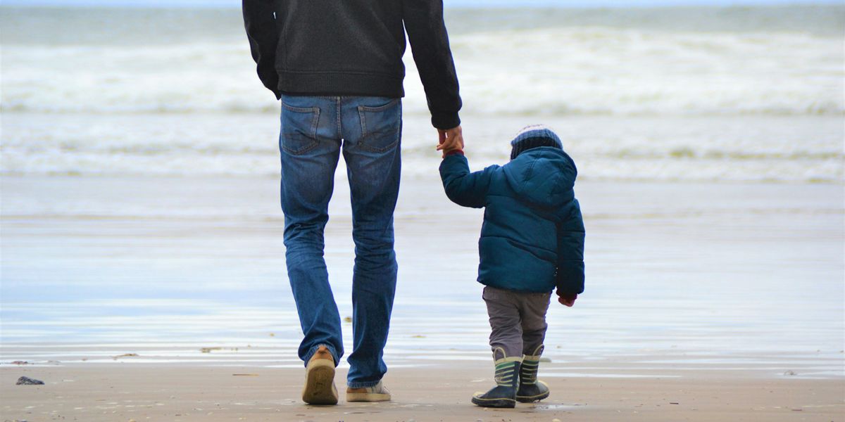 man and boy walking on seashore