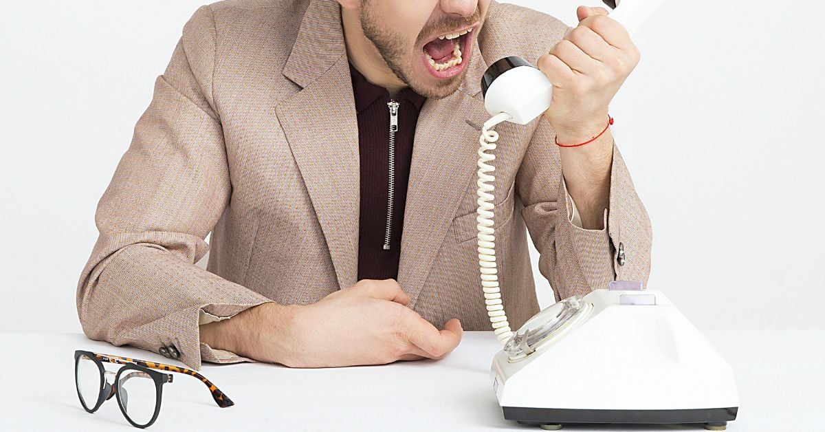 Man yelling into the receiver of a rotary phone