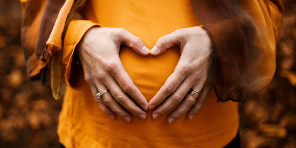 Pregnant woman forming a heart with hands over belly