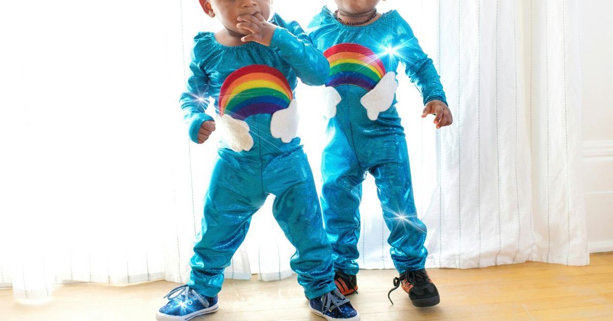 Twin toddlers in matching rainbow onesies